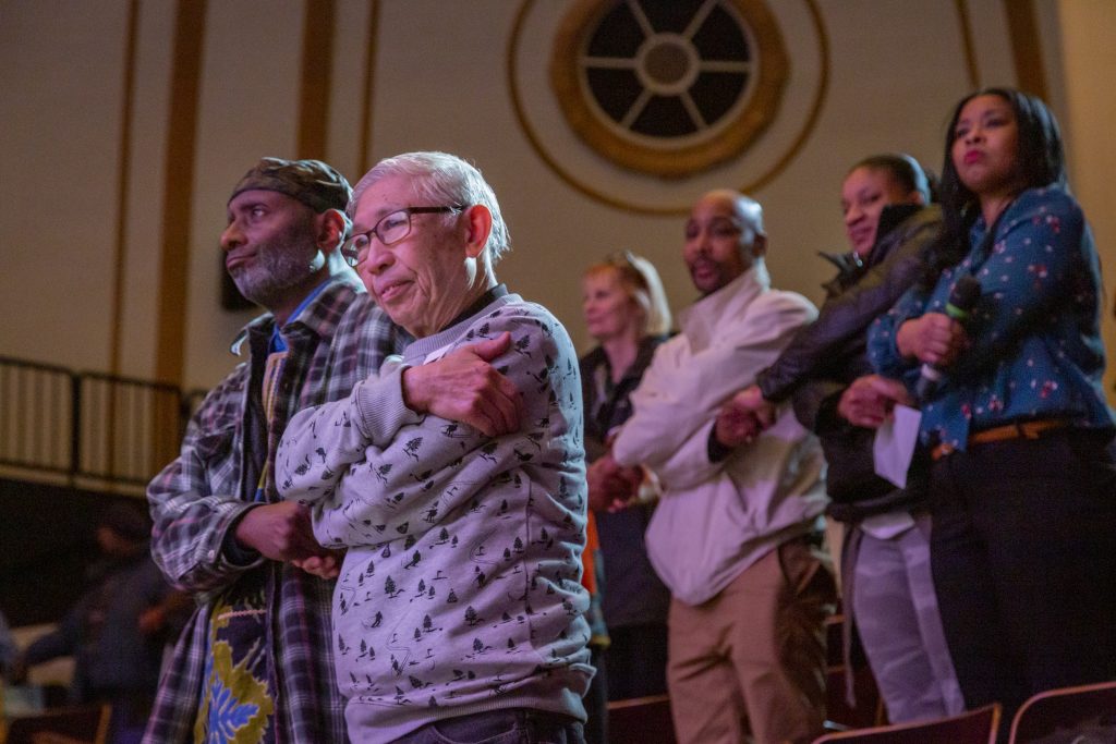 Audience members stand during the World Cancer Day Celebration, February 8, 2020, hosted by The Cierra Sisters at the Langston Hughes Performing Arts Center in Seattle, Washington.